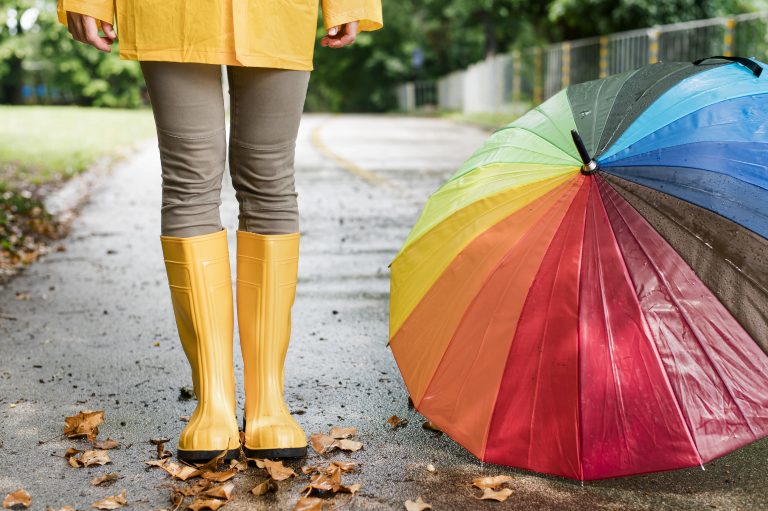 mulher-de-botas-de-chuva-ao-lado-de-guarda-chuva-colorida