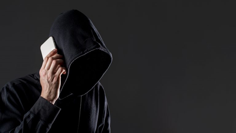 vista-lateral-hacker-masculino-falando-no-smartphone-com-espaco-de-copia